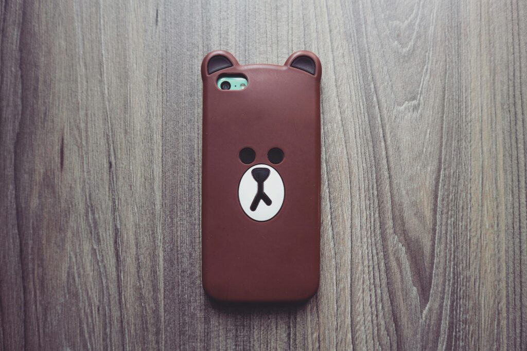 Cute bear phone case resting on a rustic wooden table, ideal for tech and lifestyle themes.